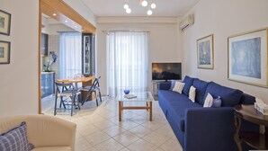 Un soggiorno con un divano blu, un tavolino, una TV e un'area pranzo con tavolo e sedie.