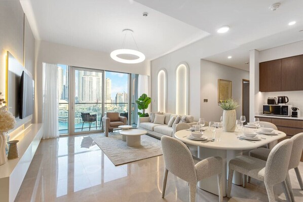 A modern living room with a dining area, large windows, and a city view.