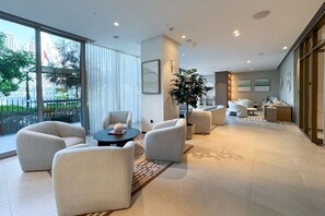 Een moderne hotellobby met een zithoek, grote ramen en uitzicht op de stad.