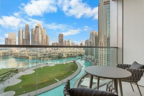 Un balcón con vistas a un paisaje urbano, una piscina y una mesa con sillas.