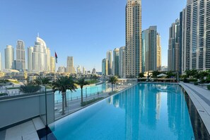 A modern hotel pool with a city skyline in the background.
