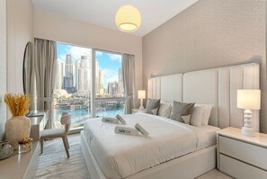 A modern hotel room with a large bed, a desk, and a view of a cityscape.