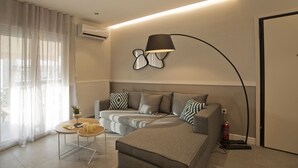 A modern living room with a sofa, a coffee table, and a lamp. - Urban Allure in Athina (Athens)