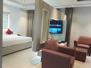 Une chambre d’hôtel moderne équipée d’un lit, d’une télévision et de deux fauteuils.