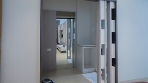A hallway with a modern design, featuring a glass door leading to a bathroom with a white sink and mirror. - HOTEL RAMKRISHNA PALACE (Bijapur)