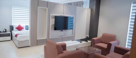 A modern living room with a flat-screen TV, a sofa set, and a coffee table.