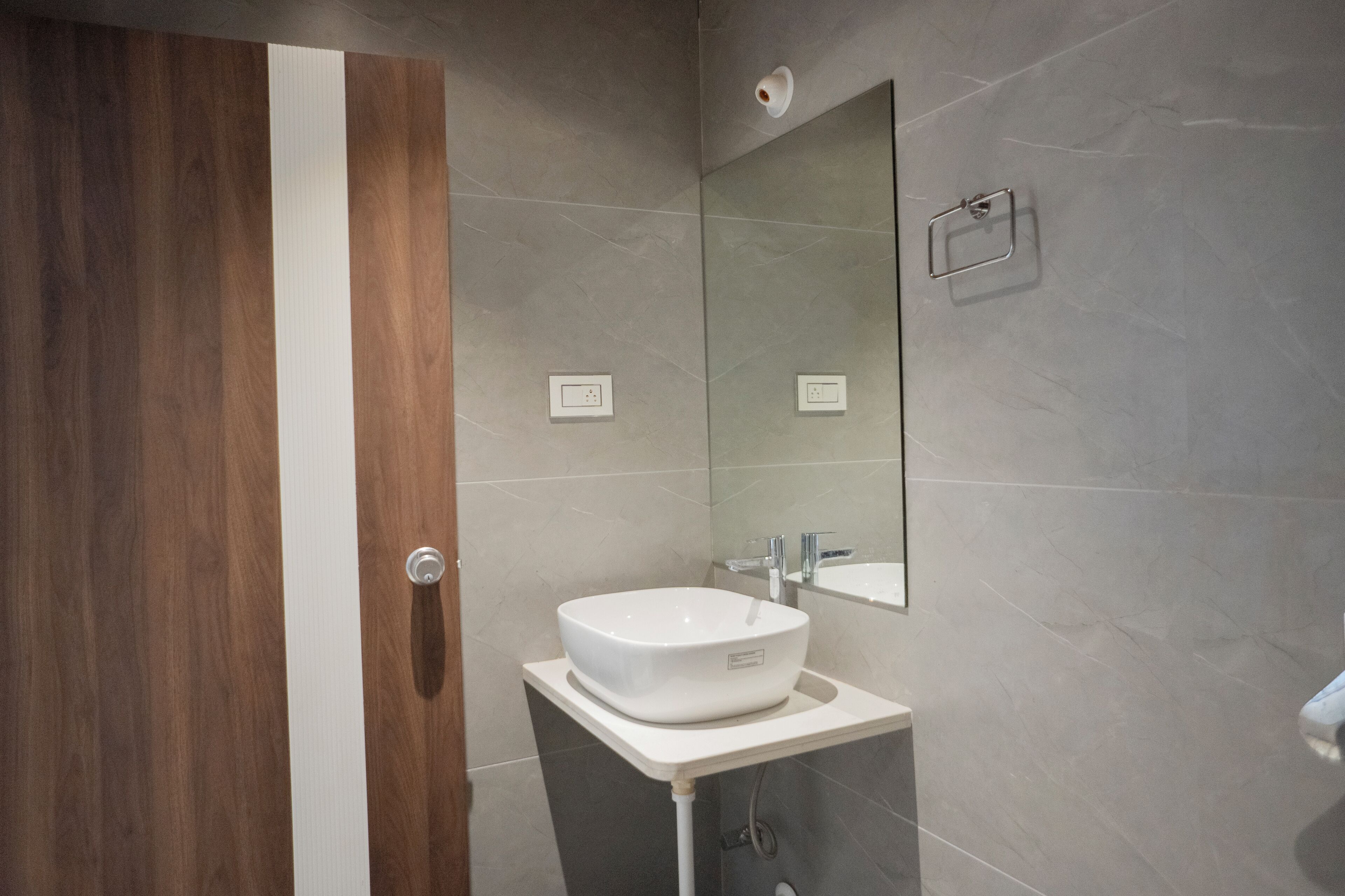 A bathroom with a wooden door, a white sink, and a mirror on the wall.