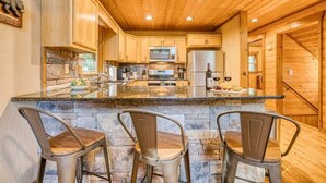 A kitchen with wooden cabinets, a stone countertop, and three bar stools.