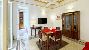 Un espace repas comprenant une table et des chaises, un téléviseur, un meuble et un tapis à motifs.