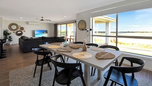 A modern dining area with a large table, black chairs, and a view of the outdoors.