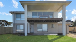 A modern two-story house with a flat roof, large windows, and a covered front porch.