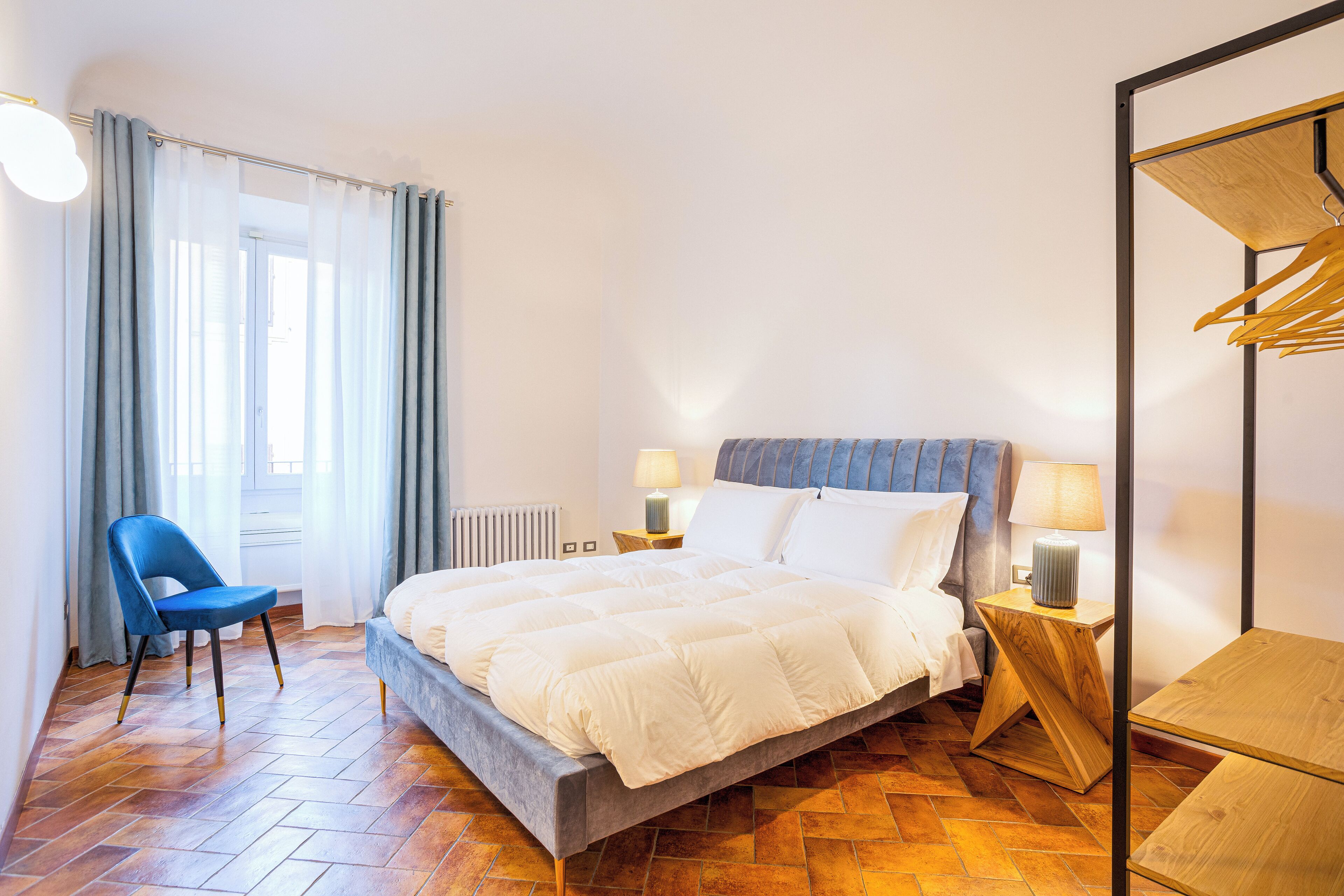 A bedroom with a bed, a chair, a nightstand, and a wooden table.