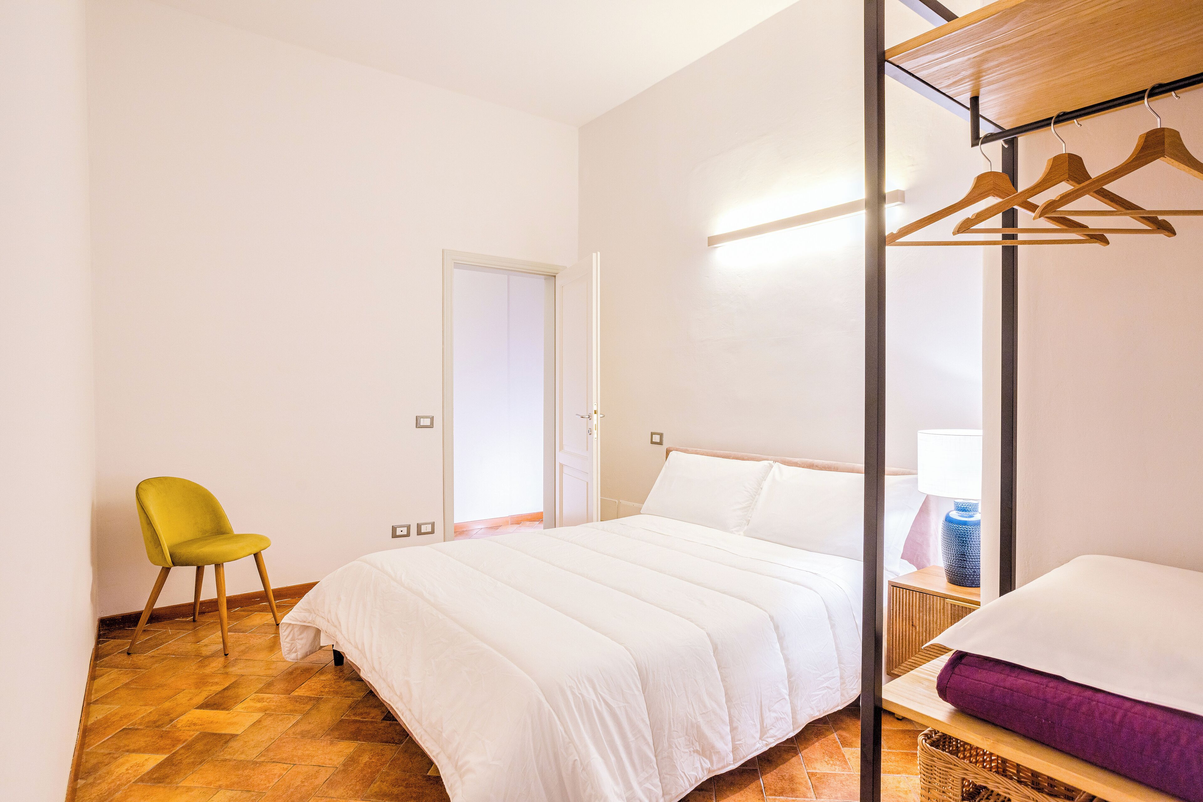 Une chambre à coucher avec un lit, une chaise, une armoire et une table de chevet.