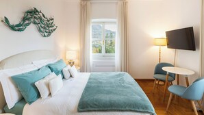 Una habitación de hotel con cama, televisión, escritorio y silla.