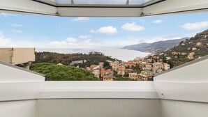 Vista desde una ventana hacia un pueblo costero con edificios y árboles.