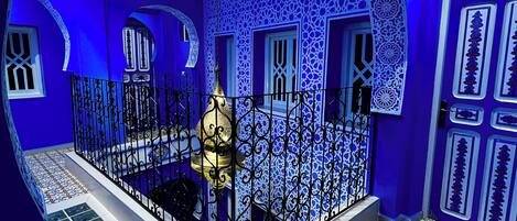 Una habitación con elaborados diseños de azulejos azules y blancos, un balcón con barandillas de metal ornamentadas y un suelo estampado.