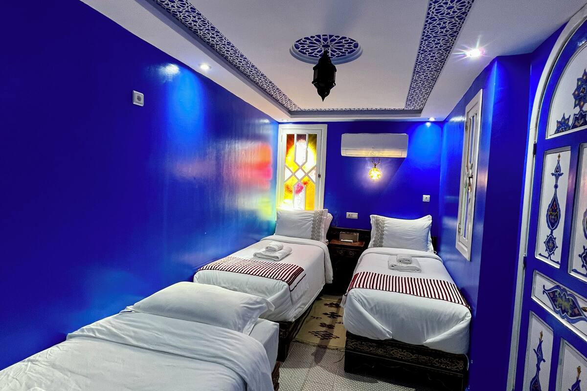 Ein Hotelzimmer mit zwei Einzelbetten, einer kleinen Sitzecke und einer dekorativen Decke.
