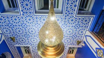 A chandelier with intricate geometric patterns and a blue and white patterned wall.