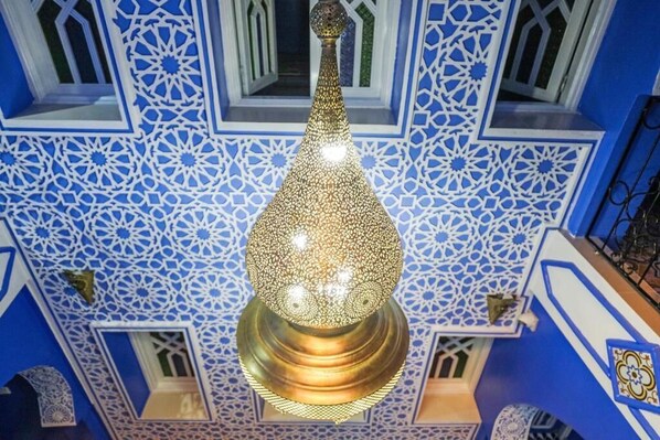 A chandelier with intricate geometric patterns and a blue and white patterned wall.
