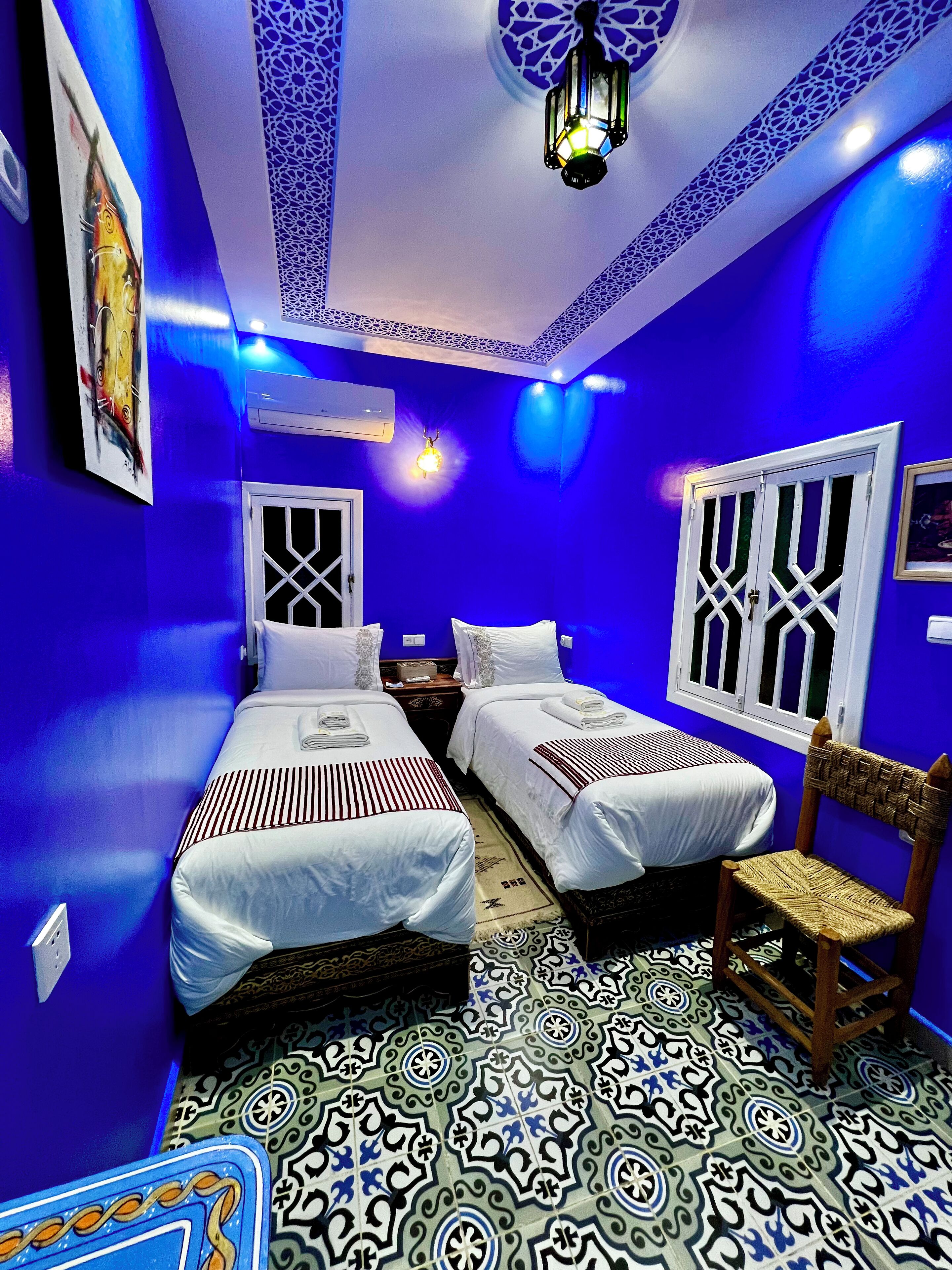 A room with two beds, a decorative ceiling, and patterned floor tiles.
