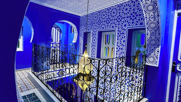 Una habitació amb mosaics blau i blanc complexos, un sostre decoratiu i un paviment amb dibuixos.