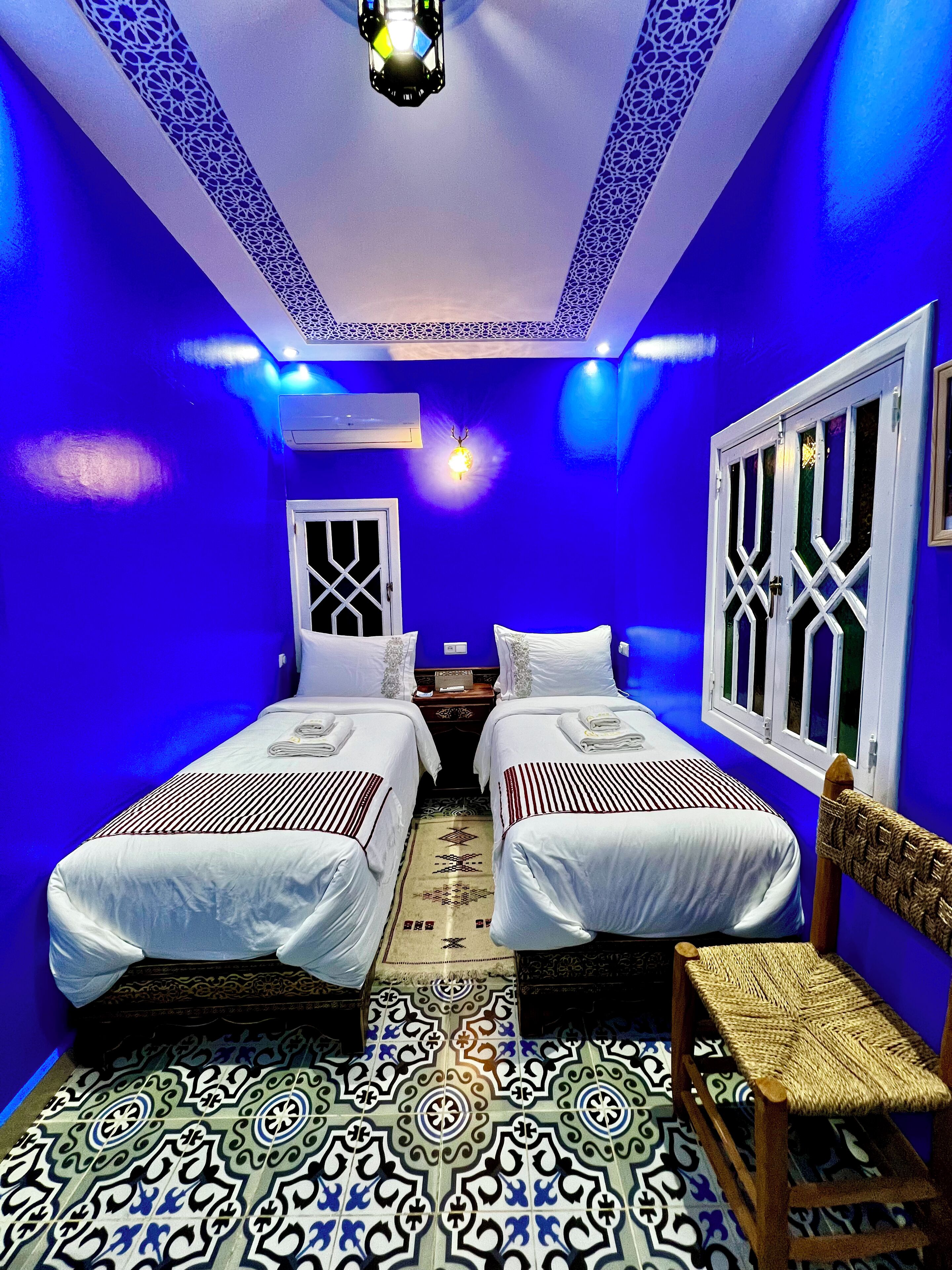 A room with two beds, a patterned floor, and blue walls.