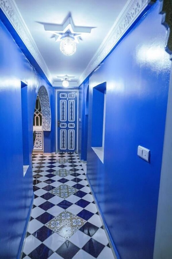 A hallway with blue walls and a checkered floor. - Riad Chengli (Chefchaouen)