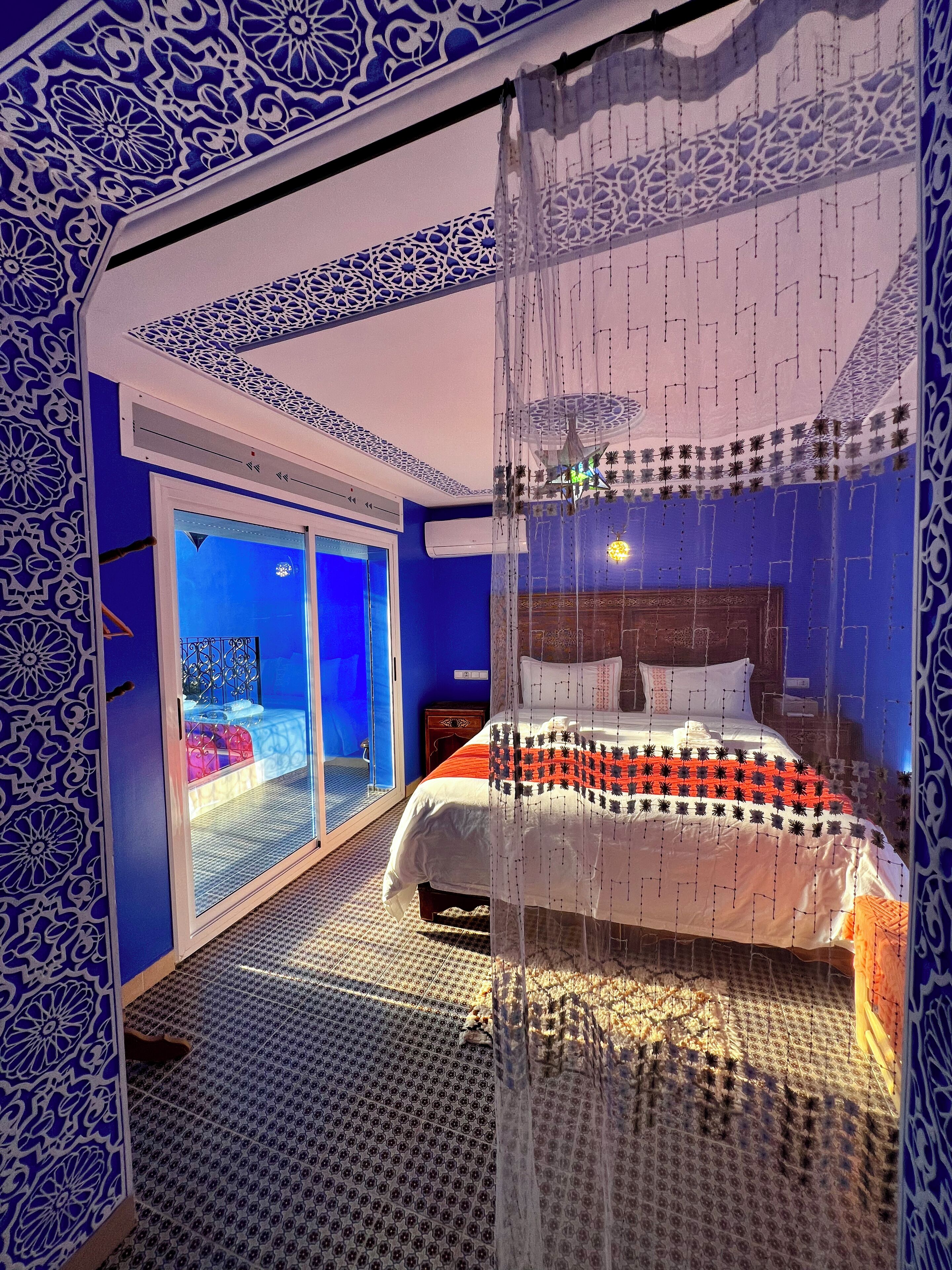 A bedroom with a bed, a window, and a patterned wall.