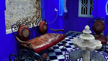 Una habitación con piso a cuadros, paredes azules y muebles de metal ornamentado.