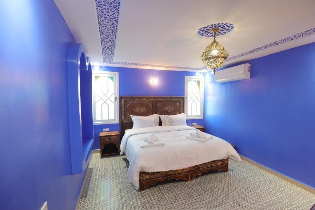 Un dormitorio con una cama grande, una lámpara decorativa en el techo y una ventana con vistas.