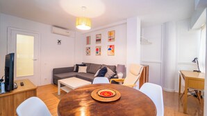 Uma sala de estar moderna com um sofá, uma mesa de jantar e uma televisão.