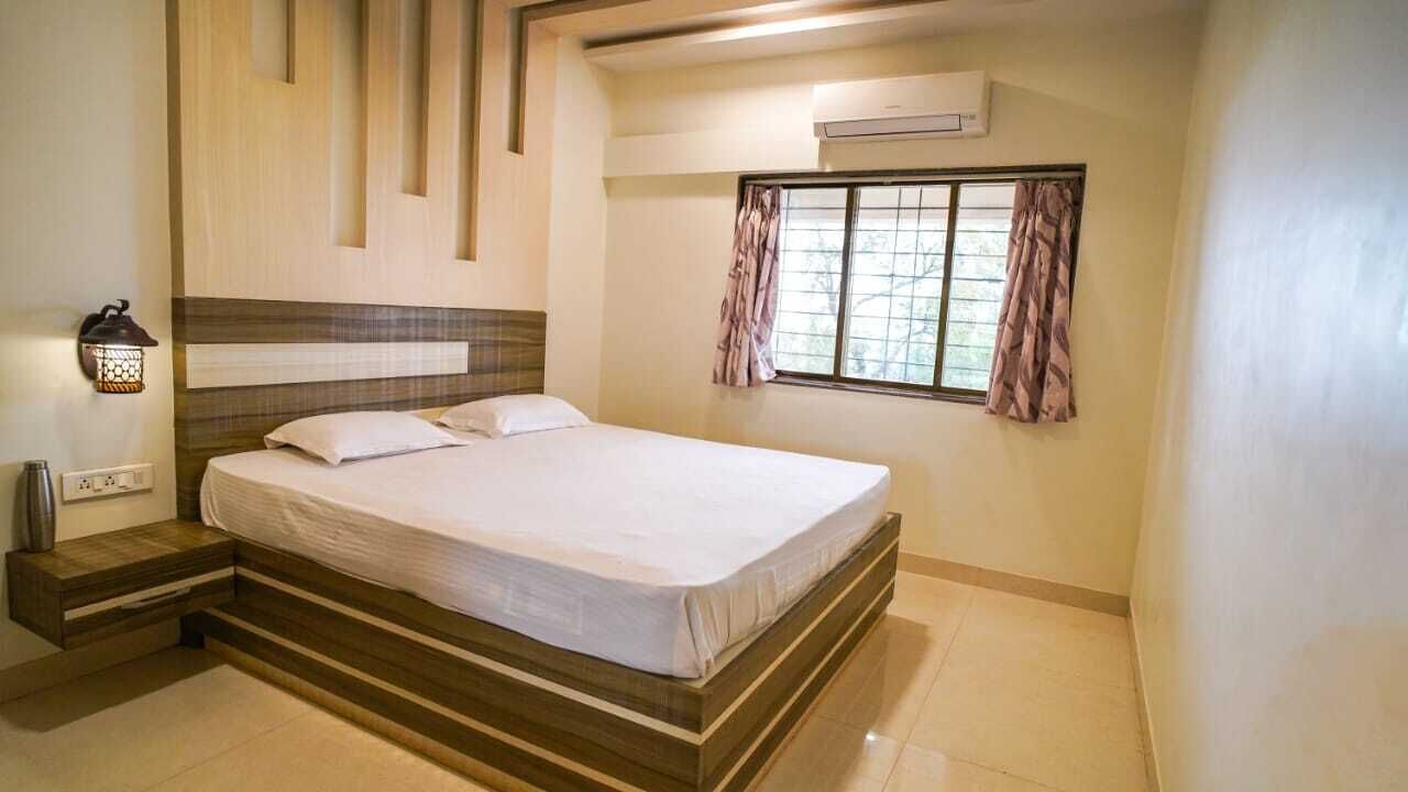 Un dormitorio con cama, mesita de noche, equipo de aire acondicionado y ventana con cortinas.