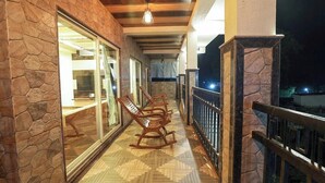 Un balcon extérieur abrité, doté d’un plancher en bois, de murs en pierre et d’une balustrade.