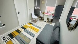 A compact living space with a kitchenette, a dining area, and a sofa. - Spacious and newly built,perfect for your getaway! (Northolt)