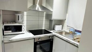 A modern kitchen with white cabinets, a microwave, a toaster, and a stove. - Spacious and newly built,perfect for your getaway! (Northolt)