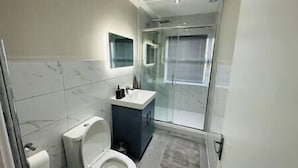 A modern bathroom with a toilet, sink, and shower area. - Stylish and Luxury Flat in LND (Uxbridge)
