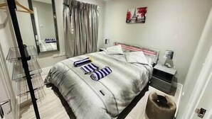 A modern bedroom with a bed, bedside tables, a mirror, and a wardrobe. - Stylish and Luxury Flat in LND (Uxbridge)