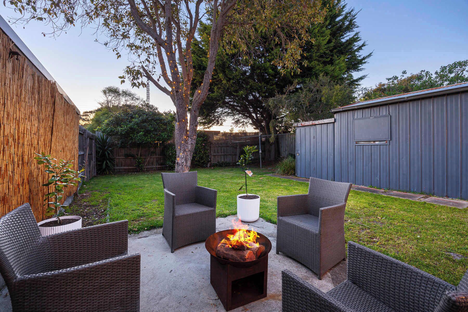 A backyard with wicker furniture, a fire pit, and a wooden fence.