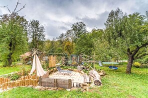 Un espace extérieur rustique avec une terrasse en bois, une balançoire et un hamac.