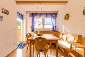 Ein Holzespeisesaal mit Stühlen, einer Bank und einem Fenster mit Vorhängen.