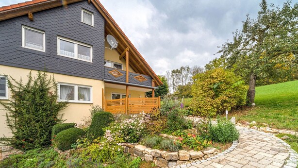 A two-story house with a stone pathway leading to the entrance. - Cozy Apartment in Marktrodach With Sauna (Marktrodach)