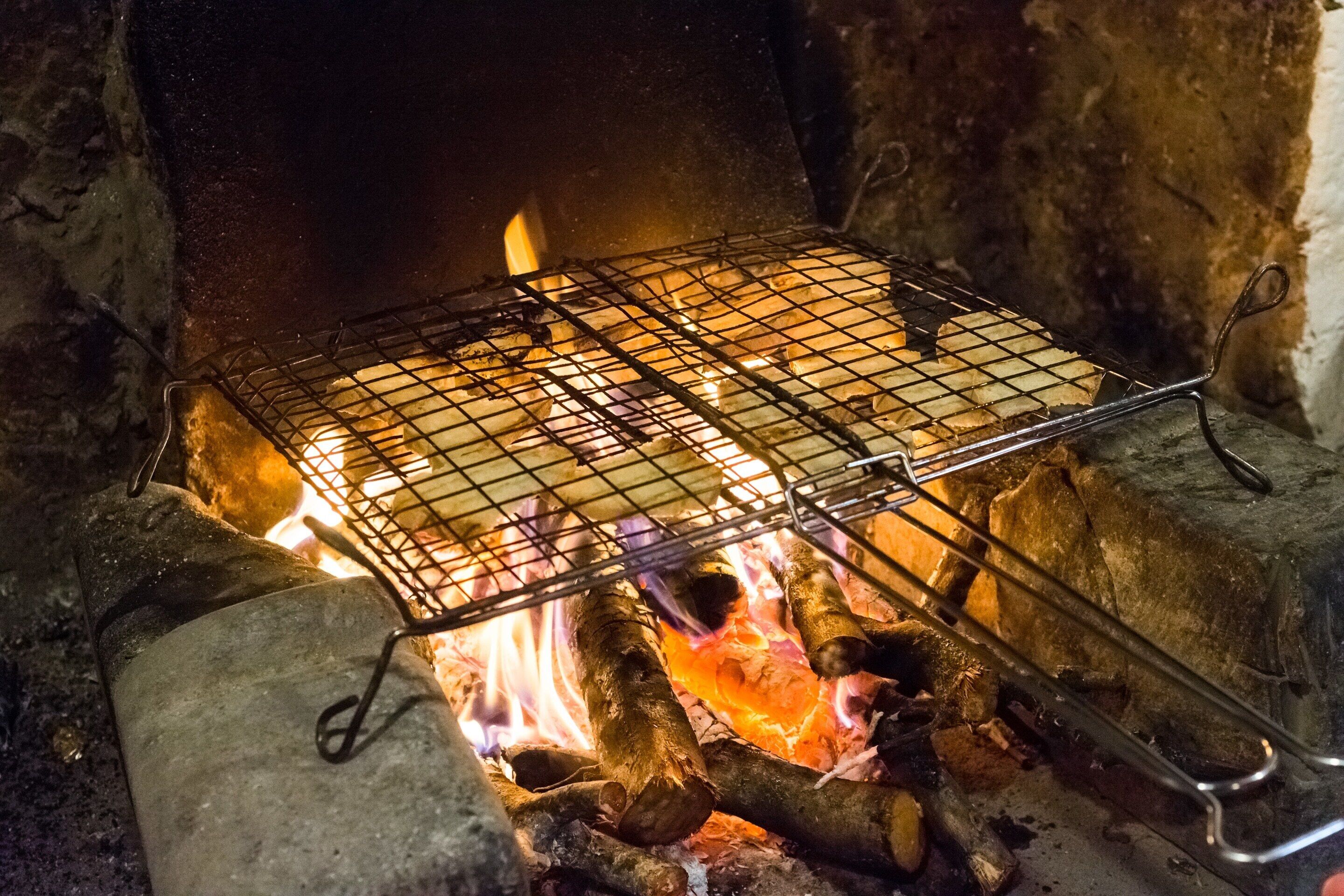 A grill over an open fire with logs and a wire rack.