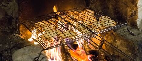 A grill over an open fire with logs and a wire rack.