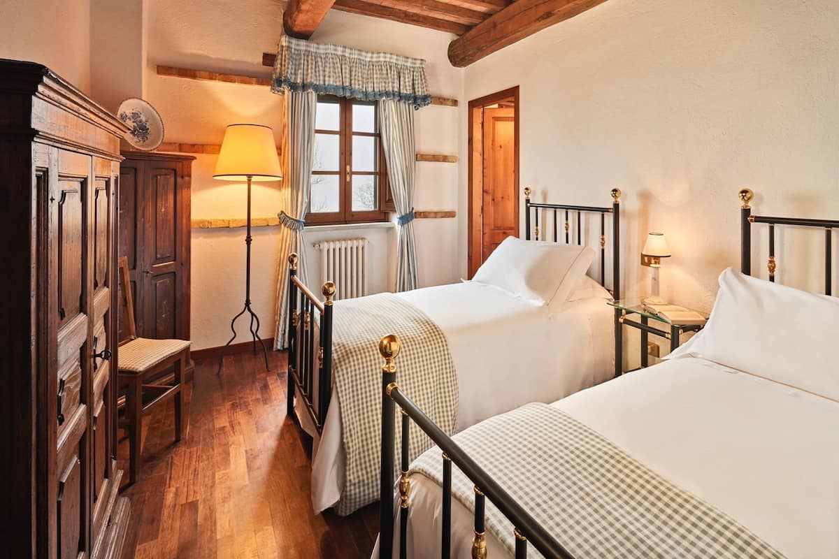 Une chambre à coucher de style traditionnel, avec deux lits simples, des meubles en bois et un design classique.
