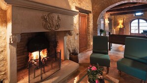 Una chimenea de piedra con fuego, techo de madera y un sillón verde.