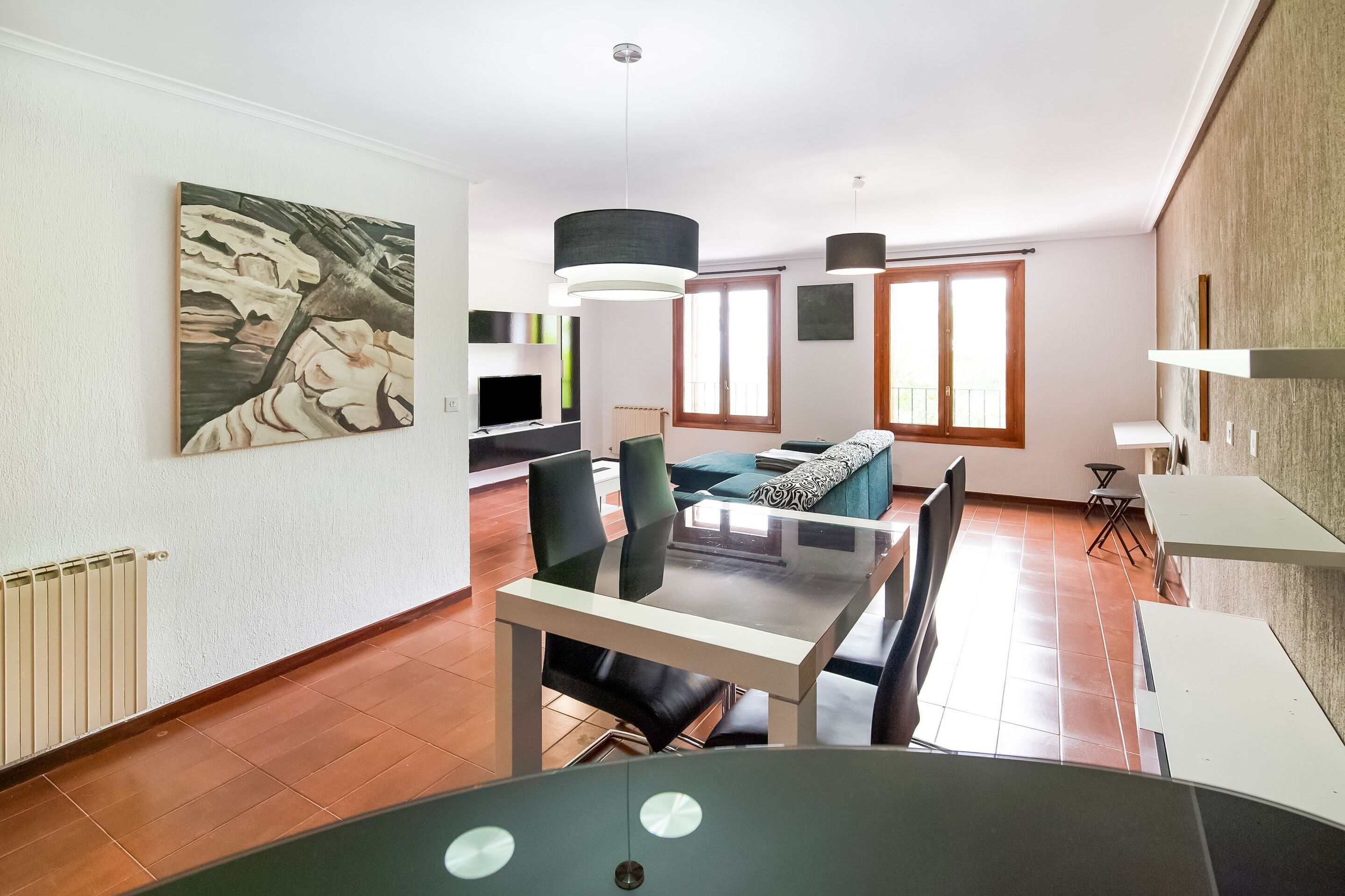 A modern living room with a dining table, chairs, a sofa, and a TV.