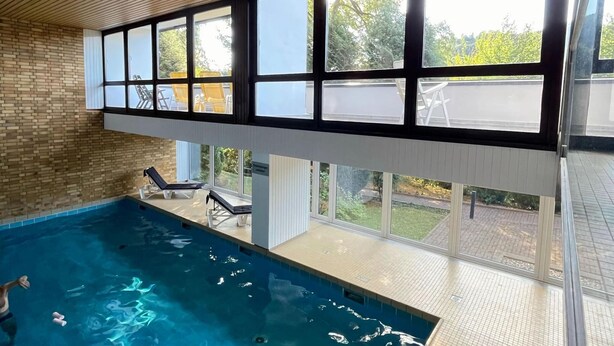 Una piscina interior con vistas al exterior a través de amplios ventanales.