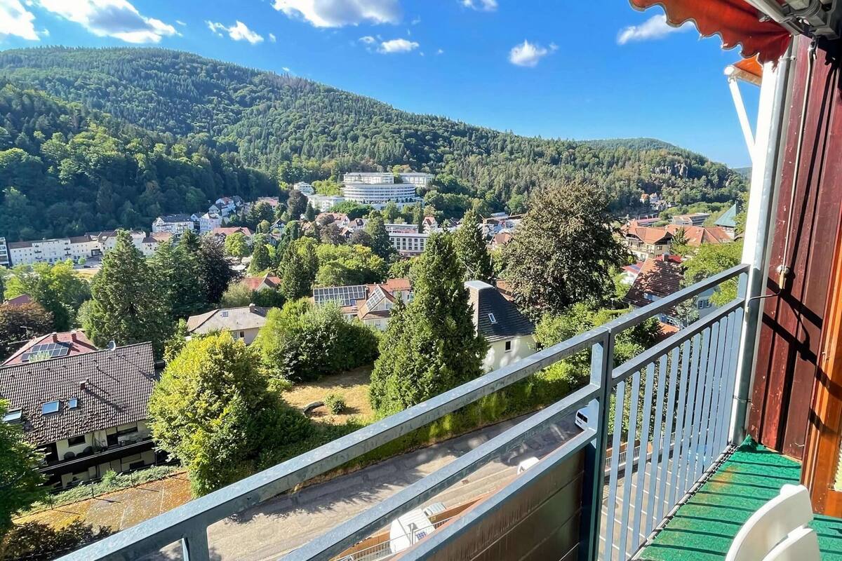 Un balcó amb vistes a una vila envoltada de turons.