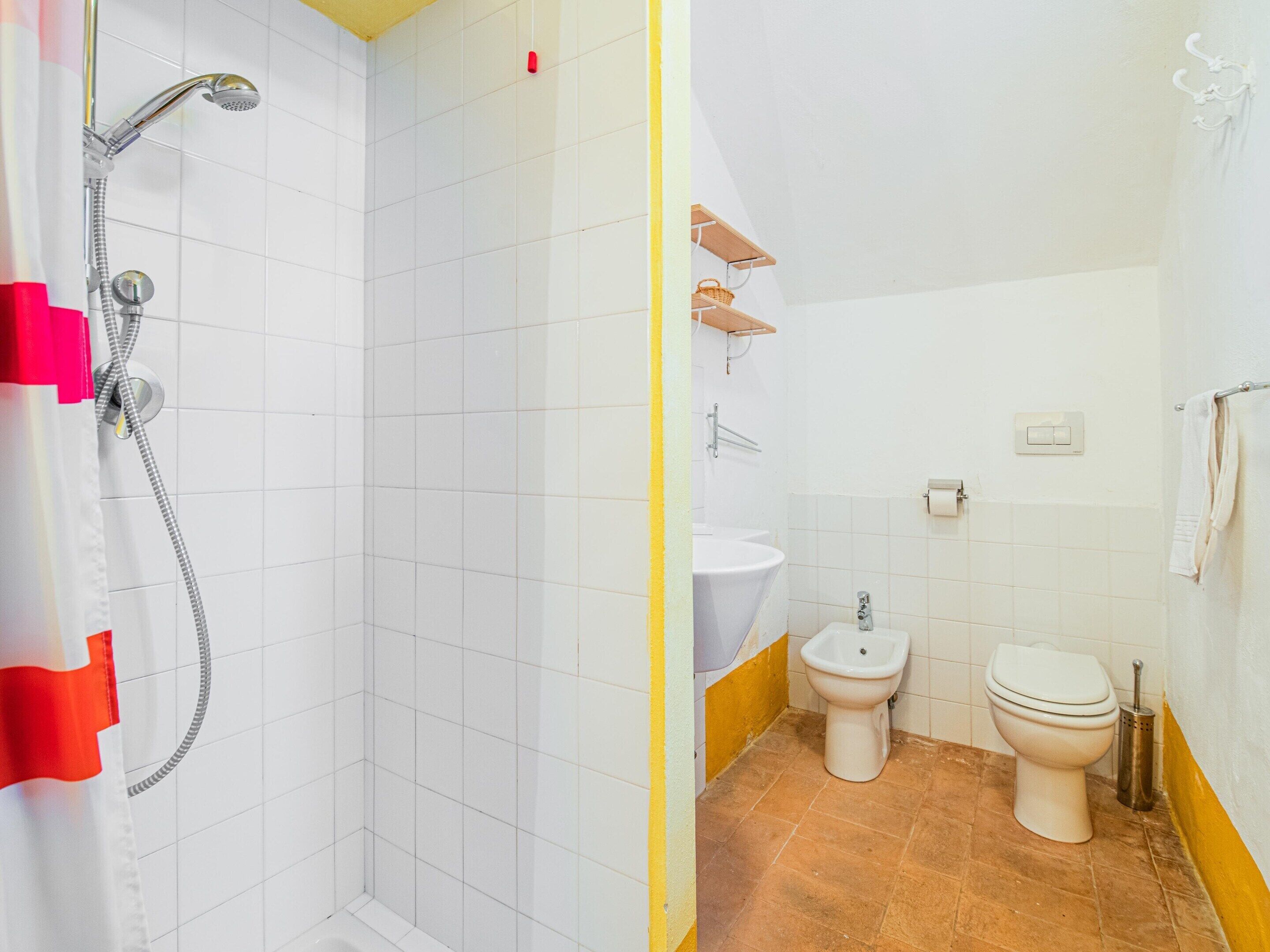Et badeværelse med bruser, toilet, bidet og vask.