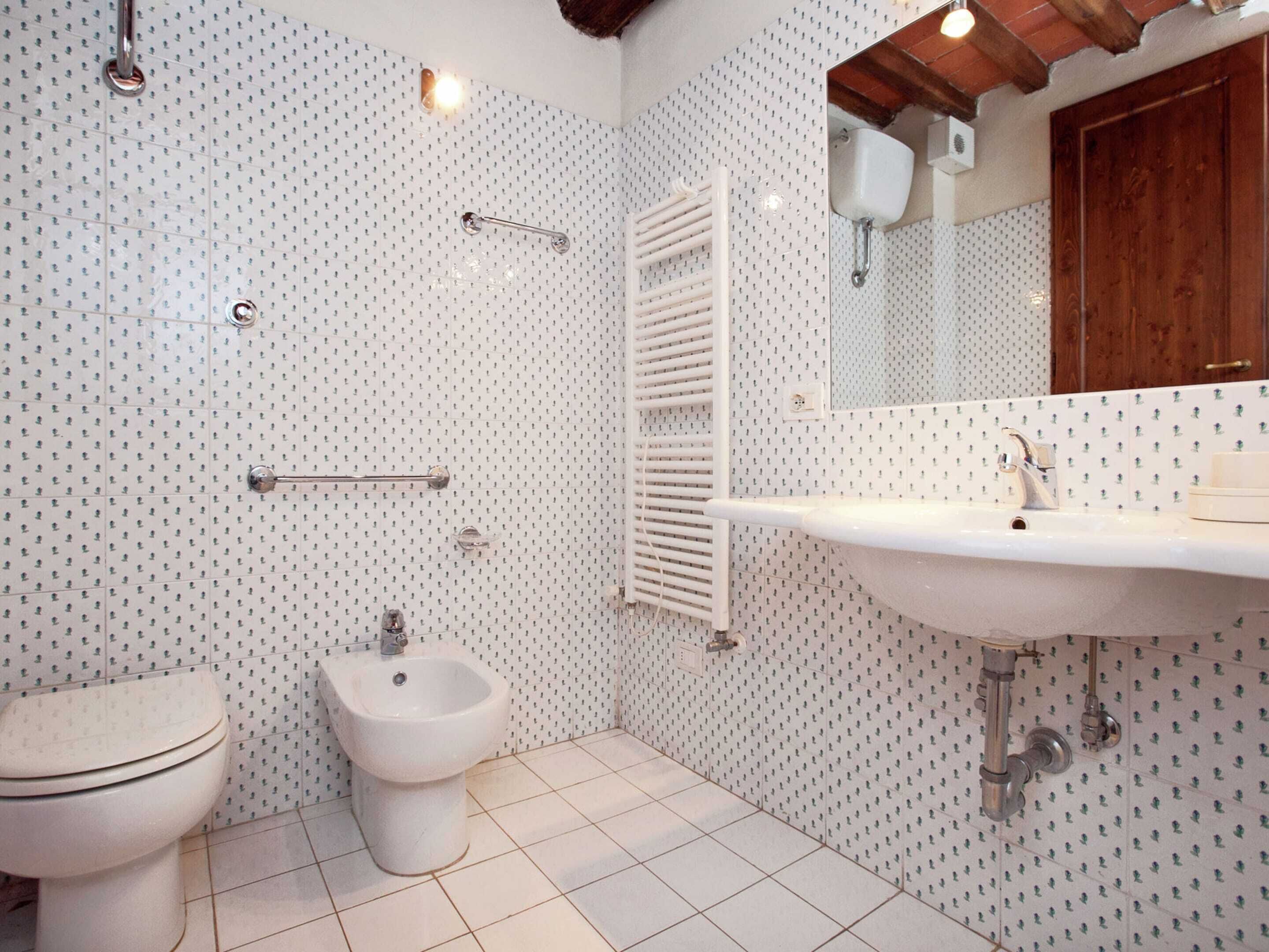 Et badeværelse med toilet, bidet, vask og træloft.